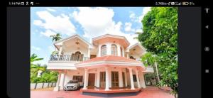 une grande maison rose avec une voiture devant elle dans l'établissement Palatial villa in Kottayam town with 6 bedrooms, à Kottayam