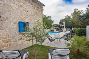 un edificio de piedra con sillas y piscina en Villa Allegra Velici en Vižinada