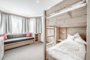 a bedroom with two bunk beds and a couch at Hotel Jenewein in Obergurgl