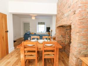 a dining room with a wooden table and a brick fireplace at Bay Tree Cottage in Richmond