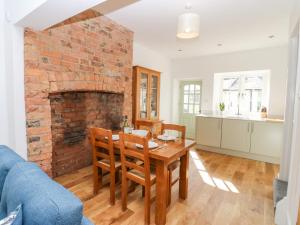 a living room with a table and a brick fireplace at Bay Tree Cottage in Richmond