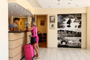 a woman standing at a counter with a pink suitcase at Rıdvan Hotel in Cesme