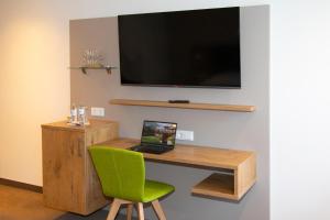 a desk with a laptop and a television on a wall at Landhotel Halbfas-Alterauge in Drolshagen