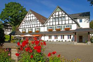 ein großes weißes Gebäude mit roten Blumen davor in der Unterkunft Landhotel Halbfas-Alterauge in Drolshagen