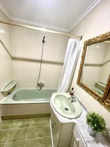 uma casa de banho com uma banheira, um lavatório e um espelho. em El piso de Sabina em Santander
