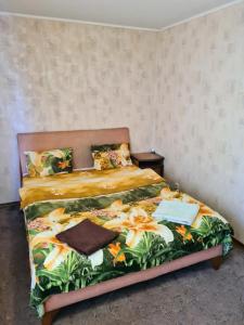 1 dormitorio con 1 cama con colcha tropical en Aparthotel VictoryHome, en Krivoy Rog