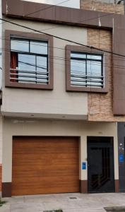 dom z drewnianymi drzwiami garażowymi i dwoma oknami w obiekcie Martina House w mieście Iquitos