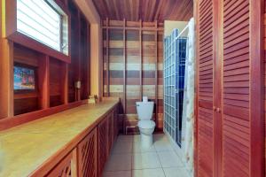 La salle de bains est pourvue de toilettes et de murs en bois. dans l'établissement Roughrider Inn Gold Standard Certified, à Caye Caulker