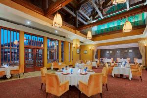 a restaurant with white tables and chairs and windows at Sheraton Hanoi Hotel in Hanoi