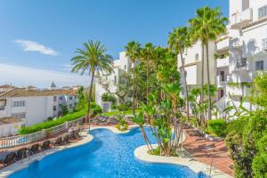 uma imagem de uma piscina num resort com palmeiras em Royal Oasis Club at Pueblo Quinta em Benalmádena