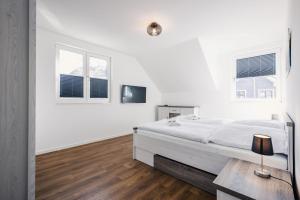 a white bedroom with a bed and two windows at Ferienhäuser Baltic Lagoon Haus 14a in Fuhlendorf