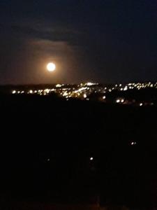 Una luna llena elevándose sobre una ciudad por la noche en Le calme de la prairie de liège, en Lieja
