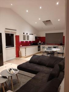 a living room with a black couch and a kitchen at Le calme de la prairie de liège in Liège