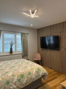 a bedroom with a bed and a flat screen tv at En-suite Double Room - Private Entrance & Free Parking in West Drayton