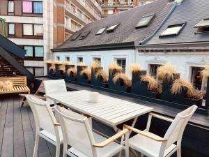 einen Tisch und Stühle auf einem Balkon mit etwas Gras in der Unterkunft Maison avec 4 suites & Rooftop - Place Saint Paul in Lüttich