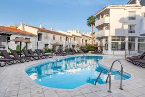 a swimming pool in a courtyard with chairs and buildings at Sahara Sunset in Benalmádena
