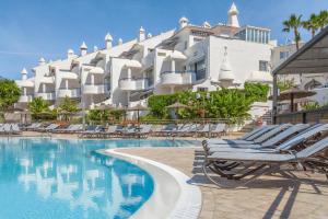 a hotel with lounge chairs next to a swimming pool at Sahara Sunset in Benalmádena