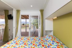 um quarto com uma cama colorida e uma varanda em Mobile home Margherita Agricamping Spineta em Cortona