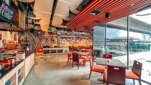 a restaurant with tables and chairs and a large window at Malyabhara Hotel - formerly Ibis Malioboro in Yogyakarta