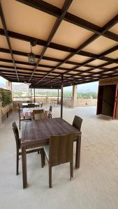 a wooden table and chairs under a roof at Alqalah Inn in Al Ḩamrāʼ