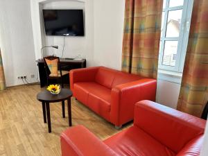 a living room with a red couch and a table at Hotel Schuetzenhaus Vorsfelde in Wolfsburg