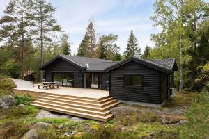 a cabin in the woods with a deck at Holiday home on Radmanso, Norrtalje with lake view in Norrtälje