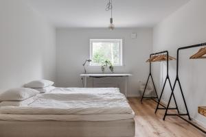 a white bedroom with a bed and a table at Holiday home on Radmanso, Norrtalje with lake view in Norrtälje