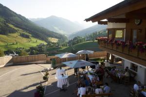 eine Gruppe von Personen, die außerhalb eines Gebäudes an Tischen sitzen in der Unterkunft Apartments Landhaus Saalbach in Saalbach-Hinterglemm