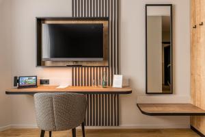 a desk with a television on a wall with a chair at Hotel & Restaurant Michaelis in Leipzig