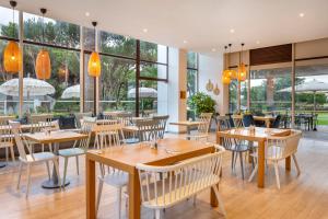 キンタ・ド・ラーゴにあるVilar do Golfの木製のテーブルと椅子、大きな窓のあるレストランを併設しています。