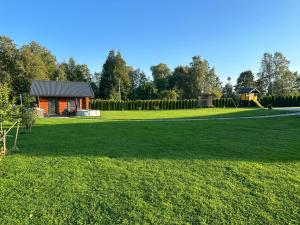 ein Haus mitten auf einem Feld mit Spielplatz in der Unterkunft Dūjas in Duķuri