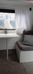 een kamer met een raam met een bank en een tafel bij Hippy caravan in Nigtevecht
