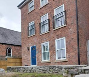 a brick building with a blue door and windows at Dee View in Holywell