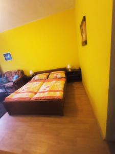 a yellow bedroom with a bed and a yellow wall at Hostinec u Kačaby in Jihlava