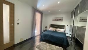 a bedroom with a bed and a large window at Rez de jardin, entre mer et montagne in Levens