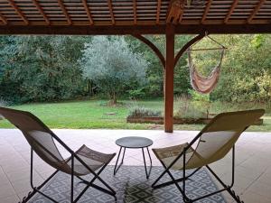 2 sillas y una mesa en un patio con hamaca en Chambre d’hôtes calme - Canal Nantes à Brest en Plessé