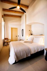 1 dormitorio con 1 cama blanca grande y ventilador de techo en Mirthea Suites, en Mírthios