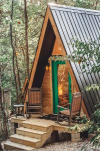 una cabaña en el bosque con dos sillas en The Green Glamping Getaway, en Rockbridge