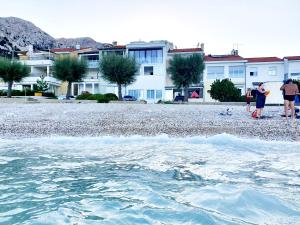eine Gruppe von Menschen, die am Strand in der Nähe des Wassers stehen in der Unterkunft Apartment Anton in Baška