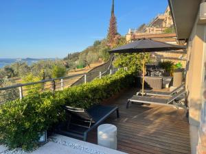 a wooden deck with benches and an umbrella at Deluxe Sunrise Sky Terrasse 2 Bedroom Design Apartment & Fantastic Lake View in Maderno