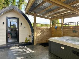 an outdoor hot tub in a building with a pergola at Paddock Pod - Sleeps 4 & Roofed Over Private Hot Tub in Burnfoot