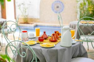 a table with breakfast food and orange juice on it at Riad Marélia in Marrakesh