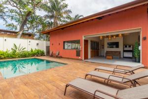 a patio with chairs and a pool in front of a house at Vila Damai Maresias in Maresias