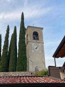a tower with a clock on it next to trees at La Volpe Rossa Rooms and Apartments in San Felice del Benaco