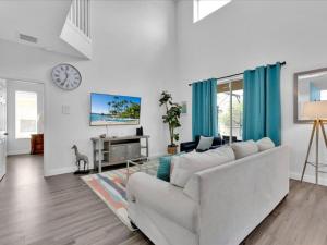 a living room with a white couch and a clock on the wall at New Beautiful Large Pool Home Near Disney-legoland in Haines City