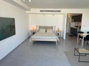 a white bedroom with a bed and a table at oR-Ya Suite in Eilat