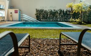 a swimming pool with two benches in front of a building at Studio a 100m Bosque, Centro e Cambuí- Home Office, Piscina, Sauna, Jacuzzi, Fitness in Campinas