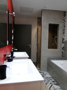 ein Badezimmer mit 2 Waschbecken und einer Badewanne in der Unterkunft Le patio d'antan, le cosy in Florémont