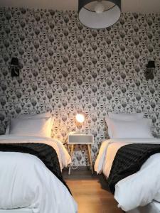 a bedroom with two beds and a wall covered in wallpaper at Le patio d'antan, le cosy in Florémont