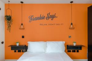 a bed with an orange wall with the words immutable saysrak dont do it at The Socialite - Covent Garden - by Frankie Says in London